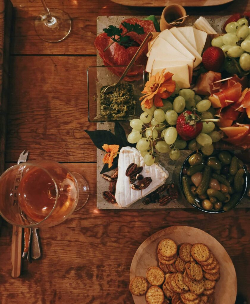 Charkbricka med kex, ost, frukt och ett glas vin.