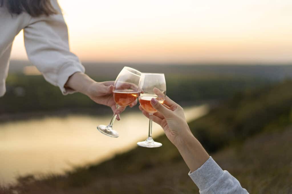 Två personer skålar med rosévin i solnedgång.