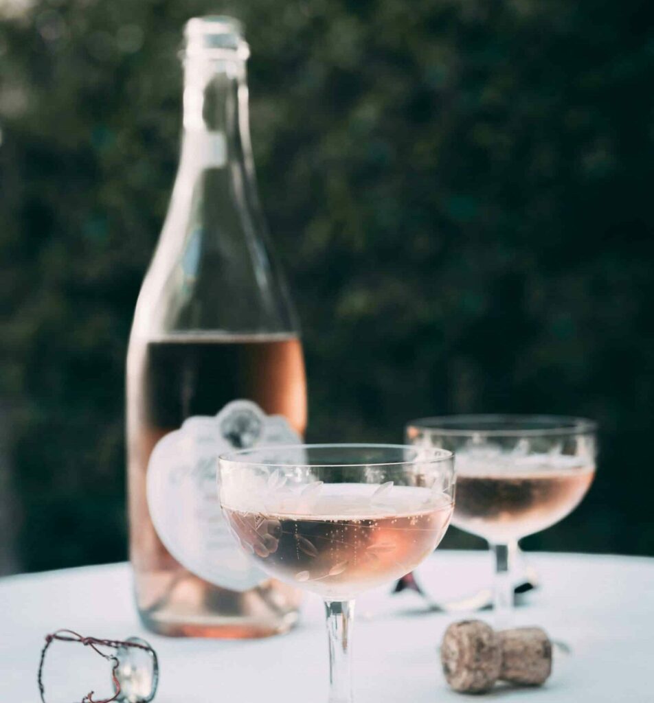 En öppnad rosevinflaska på ett bord tillsammans med två glas med rosevin.