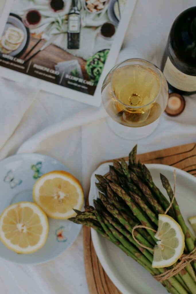 Vitt vin till matlagning på ett bord tillsammans med sparris och citroner.