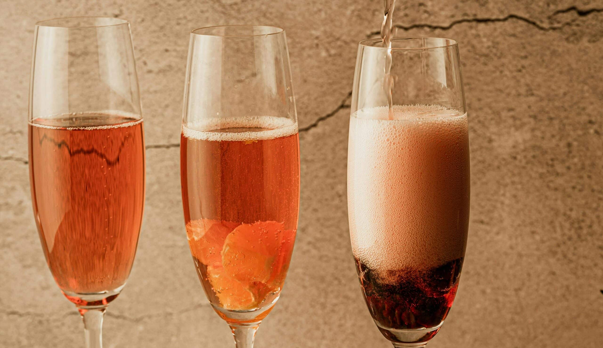 Tre champagneglas fyllda med rosévin.