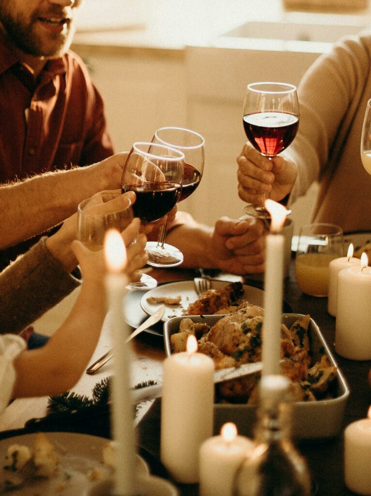 Flera personer skålar med rött vin vid ett matbord med ungsbakad kyckling.